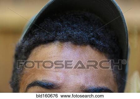 Stock Photograph - Close up of forehead and baseball cap of mixed race man. Fotosearch