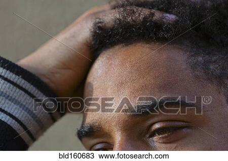 Stock Image - Close up of hand in hair of mixed race man. Fotosearch