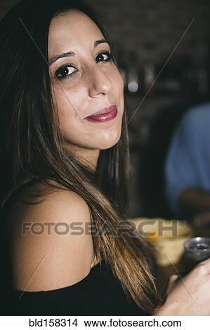 Picture - Close up of Hispanic woman drinking in nightclub. Fotosearch