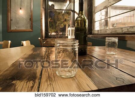 Stock Image - Close up of mason jars and wine bottle on table. Fotosearch