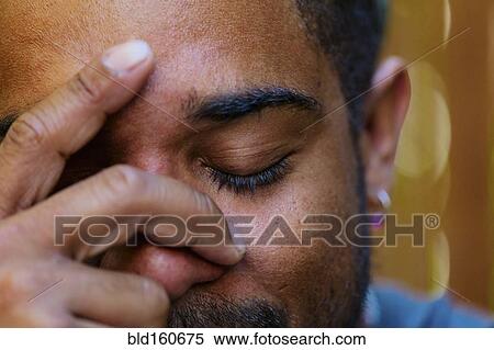 Stock Photography - Close up of mixed race man holding head in hands. Fotosearch