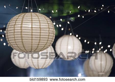 Stock Image - Close up of paper lanterns and string lights at night. Fotosearch