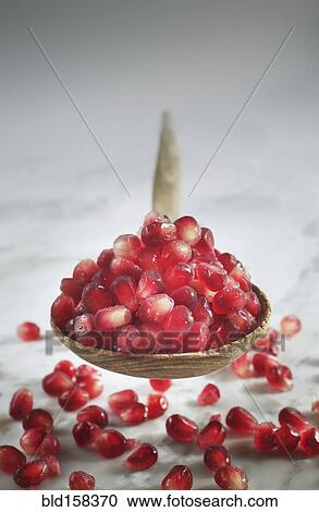Stock Image - Close up of pomegranate seeds in spoon. Fotosearch