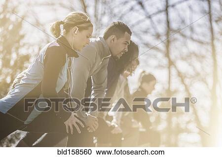 Stock Image - Close up of runners stretching in a row. Fotosearch