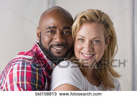 Stock Image - Close up of smiling couple hugging. Fotosearch