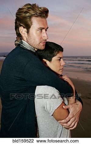 Couple hugging on beach at sunset View Large Photo Image Stock Image - Couple hugging on beach at sunset. Fotosearch