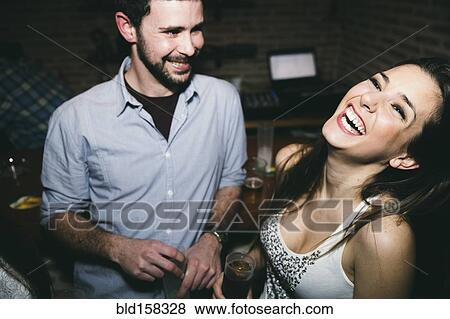 Stock Photo - Couple laughing and drinking in nightclub. Fotosearch