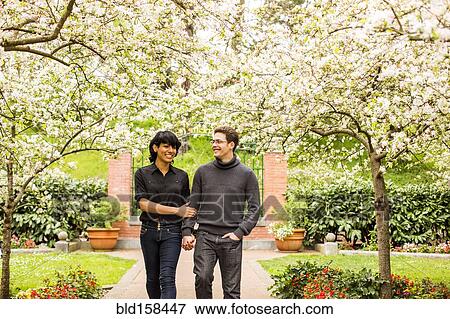 Stock Photo - Couple walking under flowering trees in park. Fotosearch