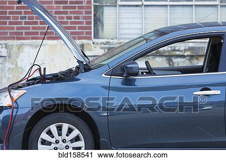 Stock Image - Empty broken down car with jumper cables. Fotosearch