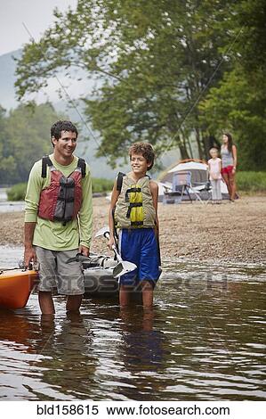 Stock Photography - Father and son pulling kayaks in remote river. Fotosearch