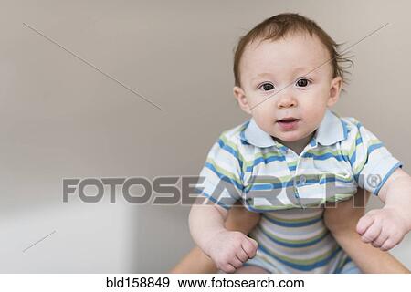 Stock Photo - Father lifting Caucasian baby. Fotosearch