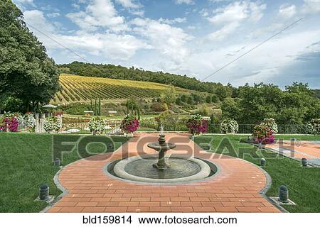 Picture - Fountain and walkway in landscaped grounds over rural fields, Radda in Chianti, Siena, Italy. Fotosearch