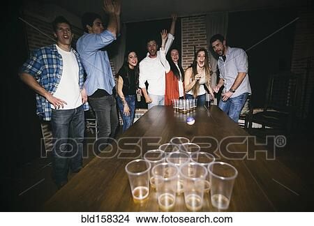 Picture - Friends playing beer pong at party. Fotosearch