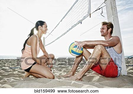 Stock Photo - Friends talking near volleyball net on beach. Fotosearch