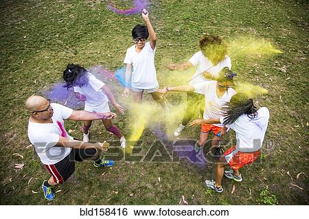 Stock Photograph - Friends throwing pigment powder in playful fight. Fotosearch