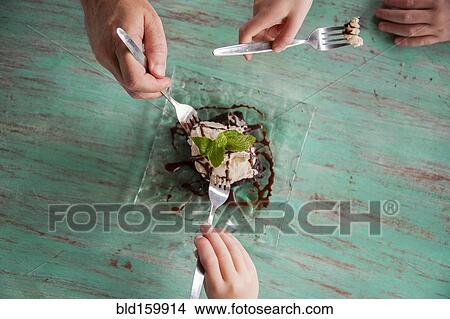 High angle view of hands reaching for food on plate View Large Photo Image Picture - High angle view of hands reaching for food on plate. Fotosearch