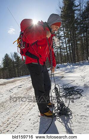 Stock Photograph - Hiker untangling ropes in snowy forest. Fotosearch