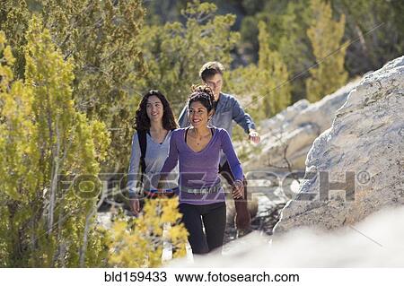 Stock Image - Hikers climbing rocky hillside. Fotosearch