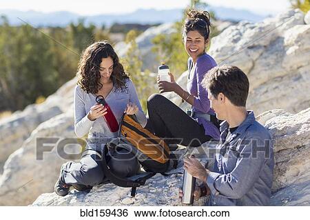 Stock Photograph - Hikers resting on rocky hillside. Fotosearch