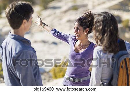 Stock Image - Hikers talking on rocky hilltop. Fotosearch