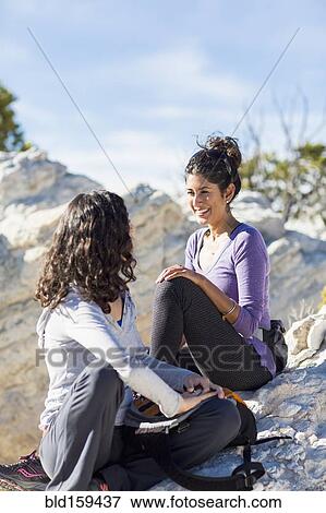 Hikers talking on rocky hilltop View Large Photo Image Stock Photo - Hikers talking on rocky hilltop. Fotosearch