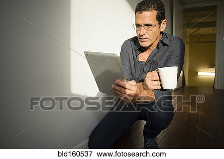Hispanic businessman using digital tablet in office hallway View Large Photo Image Stock Photo - Hispanic businessman using digital tablet in office hallway. Fotosearch