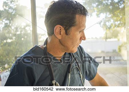 Stock Image - Hispanic doctor looking out window. Fotosearch