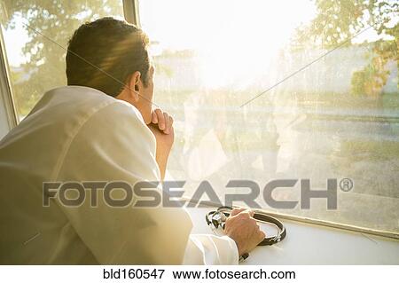 Stock Photo - Hispanic doctor looking out window. Fotosearch