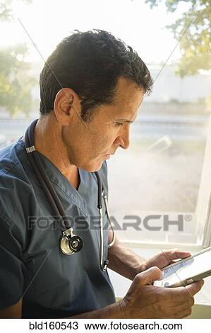 Hispanic doctor using cell phone near window View Large Photo Image Stock Image - Hispanic doctor using cell phone near window. Fotosearch
