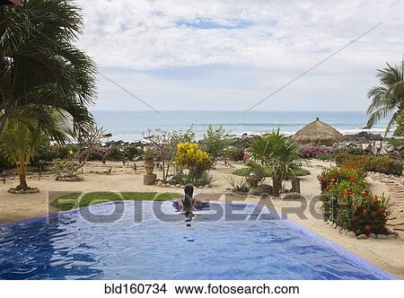 Picture - Hispanic woman relaxing in swimming pool. Fotosearch