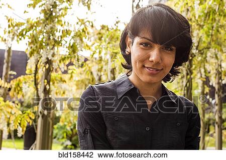 Stock Image - Hispanic woman smiling in park. Fotosearch