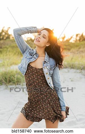 Stock Image - Hispanic woman standing on beach. Fotosearch