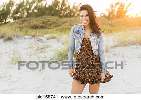 Stock Image - Hispanic woman standing on beach. Fotosearch