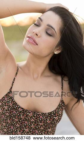 Stock Photo - Hispanic woman with eyes closed outdoors. Fotosearch