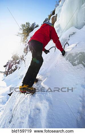 Stock Photo - Ice climber scaling snowy frozen rock formations. Fotosearch