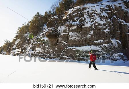 Stock Image - Ice climber walking in snowy field. Fotosearch