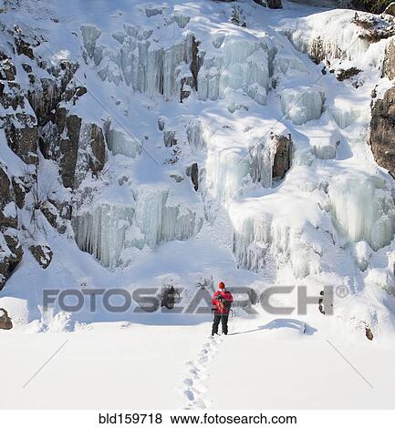 Stock Photo - Ice climber walking toward frozen rock formations. Fotosearch
