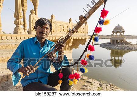 Indian man holding traditional instrument near monument, Jaisalmer, Rajasthan, India View Large Photo Image Stock Photo - Indian man holding traditional instrument near monument, Jaisalmer, Rajasthan, India. Fotosearch