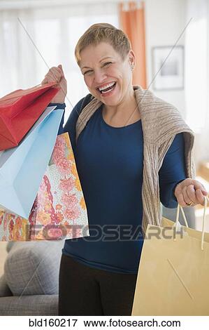 Stock Photo - Laughing Caucasian woman holding shopping bags. Fotosearch
