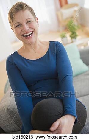 Laughing Caucasian woman sitting on sofa View Large Photo Image Stock Photograph - Laughing Caucasian woman sitting on sofa. Fotosearch
