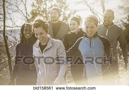 Stock Image - Laughing friends walking on forest path. Fotosearch