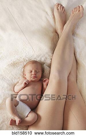 Legs of mother laying on bed with newborn baby View Large Photo Image Stock Image - Legs of mother laying on bed with newborn baby. Fotosearch