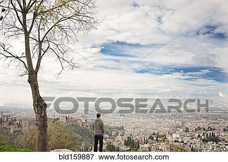 Stock Photo - Man admiring scenic view of cityscape, Granada, Spain. Fotosearch