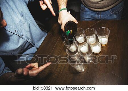 Stock Image - Man pouring drinks at party. Fotosearch