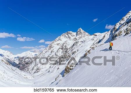 Stock Photography - Man skiing on snowy slope in remote landscape. Fotosearch