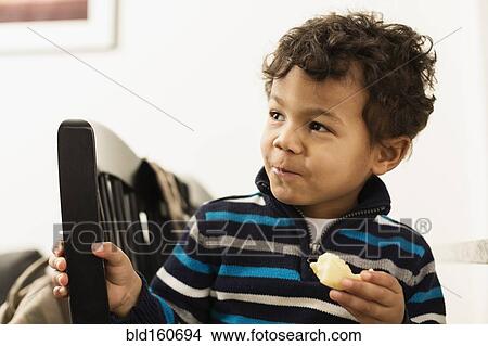 Picture - Mixed race boy eating at counter. Fotosearch