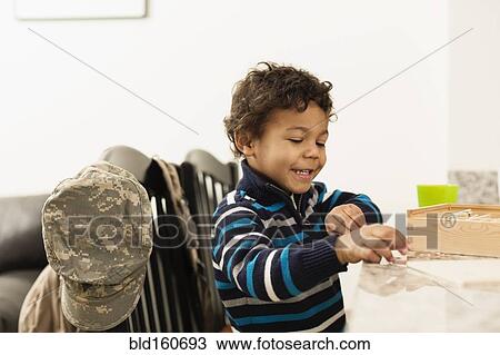 Mixed race boy playing at counter near camouflage cap View Large Photo Image Stock Image - Mixed race boy playing at counter near camouflage cap. Fotosearch