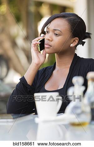 Mixed race businesswoman talking on cell phone at outdoor cafe View Large Photo Image Stock Image - Mixed race businesswoman talking on cell phone at outdoor cafe. Fotosearch