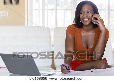 Stock Photograph - Mixed race businesswoman talking on cell phone. Fotosearch