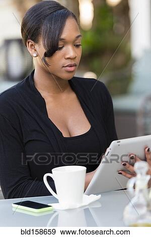 Stock Photo - Mixed race businesswoman using digital tablet at outdoor cafe. Fotosearch